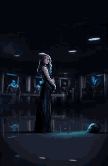 a pregnant woman stands next to a man in a suit in a dark room