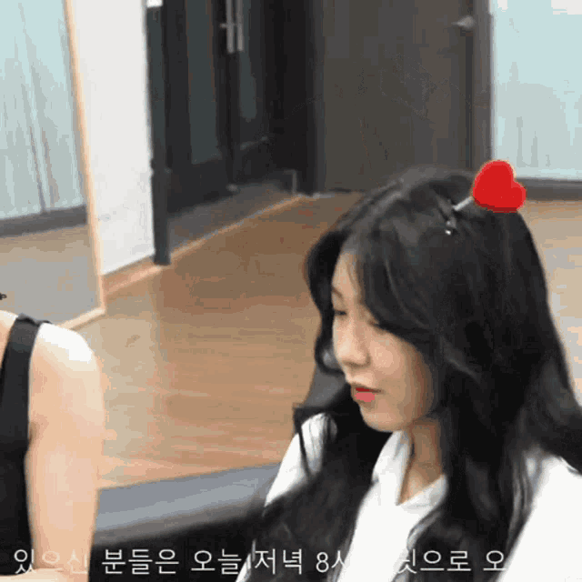 a woman wearing a heart shaped hair clip with korean writing on it