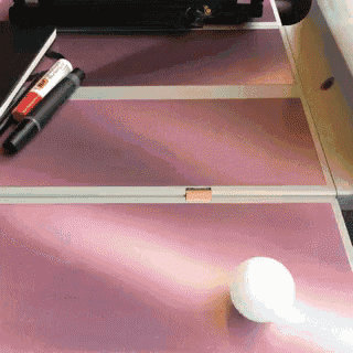 a white ball is sitting on a pink table next to a marker