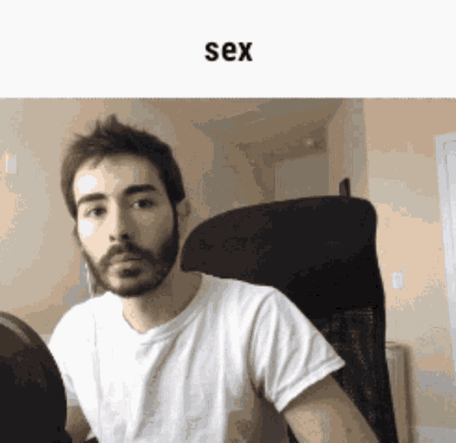 a man with a beard is wearing a white shirt and sitting in a chair with the word sex above him