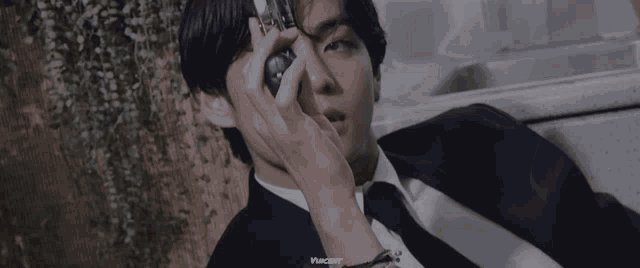 a man in a suit and tie is holding a camera to his eye .