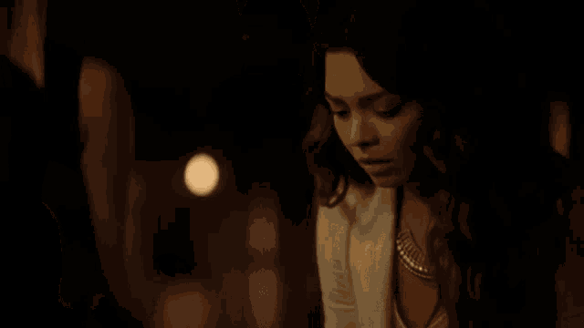 a woman in a white jacket and gold necklace is looking down