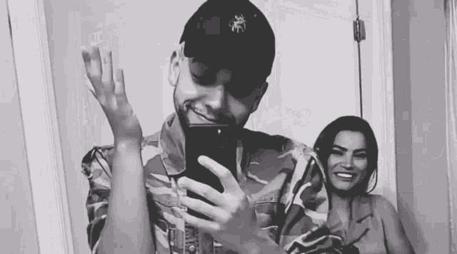 a man and a woman are taking a selfie in a mirror .