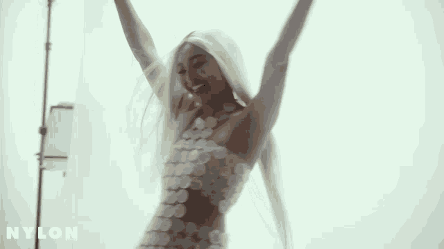 a woman in a white dress with her arms in the air is dancing .