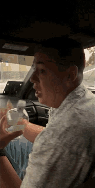 a man sitting in a car with a bottle of water in his hand