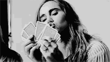 a woman is blowing a kiss while holding a handful of playing cards .