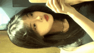 a woman with long black hair is looking at herself in a mirror
