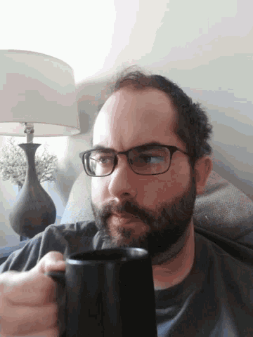 a man with glasses is holding a black mug