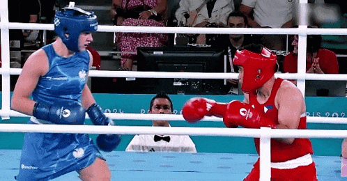 two female boxers are fighting in a ring and one of them has the letter o on her gloves