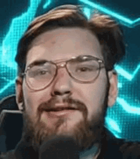 a man with a beard wearing glasses and a microphone .