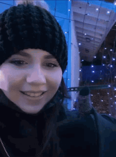 a woman wearing a black knitted hat and scarf smiles
