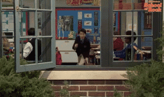 a boy in a school uniform looks out a window at a classroom with a sign that says school break
