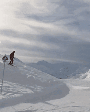 a person laying in the snow with a mountain in the background and a t on the bottom right