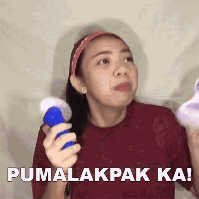 a woman in a red shirt is holding a blue object and says pumalakpak ka