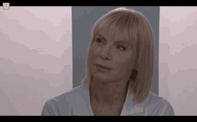 a woman 's face is shown on a tv screen with the number 12 in the corner