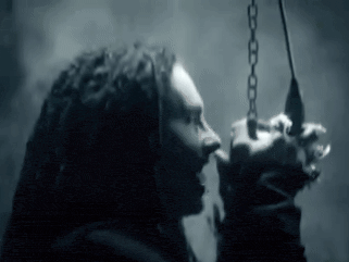 a woman with dreadlocks is holding a chain in her hand and screaming .