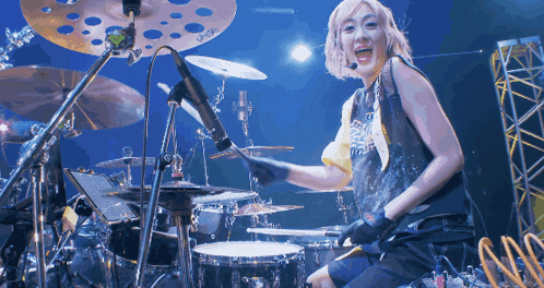 a woman is playing drums and wearing a shirt that says ' i 'm a freak ' on it