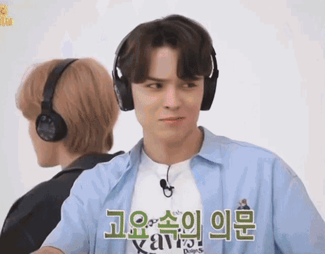 a man wearing headphones is standing next to another man and making a funny face .