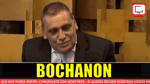 a man in a suit and tie is sitting in front of a sign that says bocanon