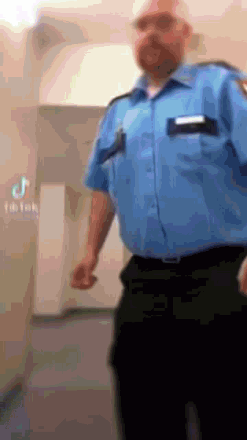 a man in a blue shirt and black pants is standing in front of a wall with tik tok written on it