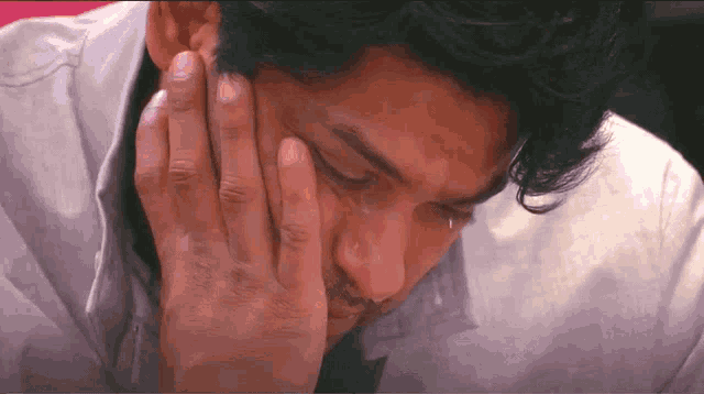 a man with a hand on his face is crying
