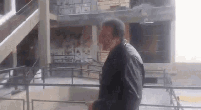 a man in a black jacket is standing in front of a building with stairs .