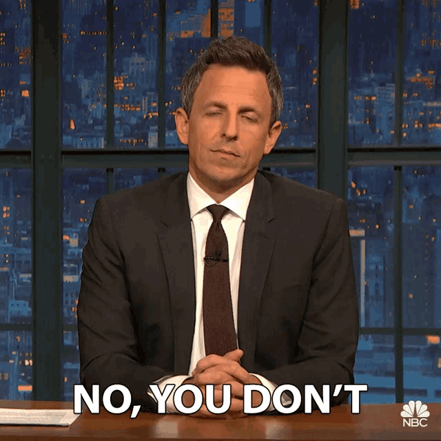 a man in a suit and tie says " no you don 't " while sitting at a desk