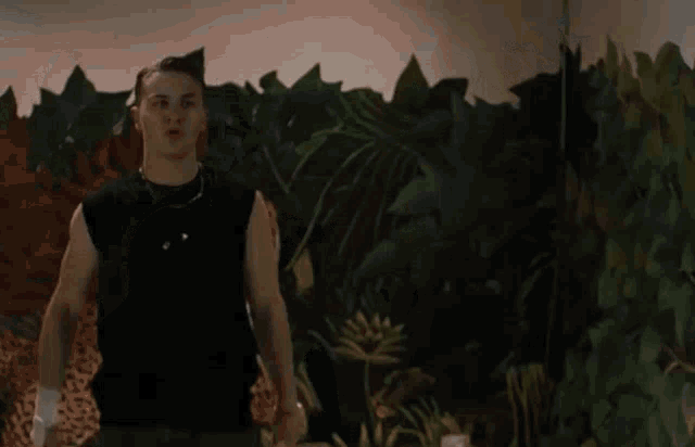 a man with a bandage on his hand is standing in front of a wall with a painting of a jungle on it .