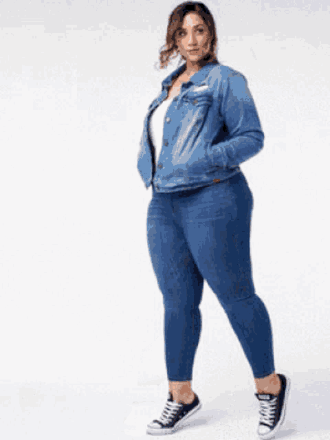 a plus size woman is sitting on a stool wearing a grey shirt and blue jeans