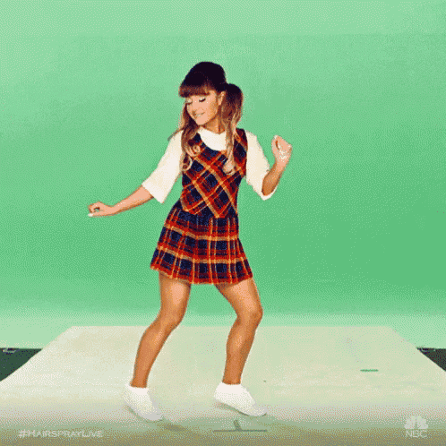 a woman in a plaid dress is dancing on a green screen .