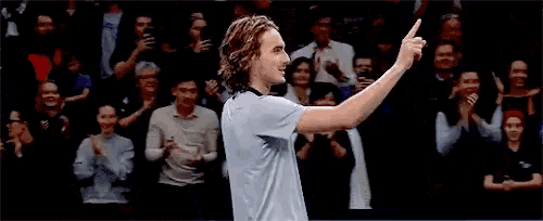 a tennis player is standing in front of a crowd of people .