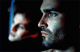 a close up of a man 's face with a beard looking at a mirror .