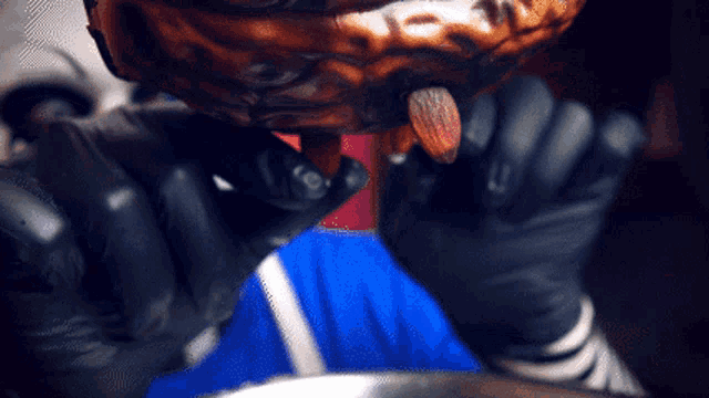 a person wearing black gloves is holding an almond