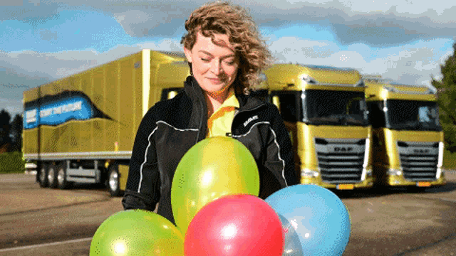 a woman holding balloons in front of a truck that says daf on it