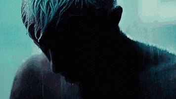 a man is taking a shower in a dark room with water coming out of his mouth .