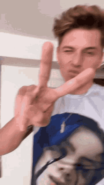 a man wearing a shirt with a picture of a woman on it giving the peace sign