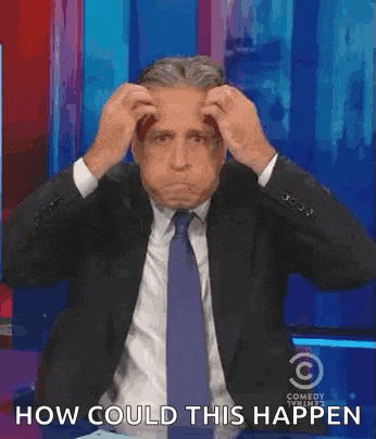 a man in a suit and tie is holding his hands to his head while sitting on a stage .