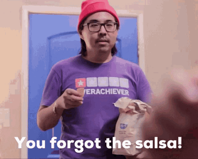 a man wearing a purple shirt that says " you forgot the salsa " is holding a bag of chips