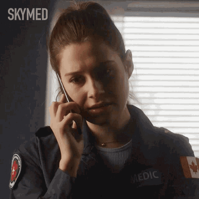 a woman in a skymed uniform is talking on a cellphone