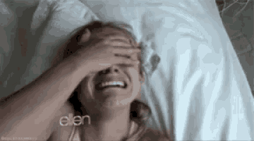 a woman is laying in a bed with her hand on her face .