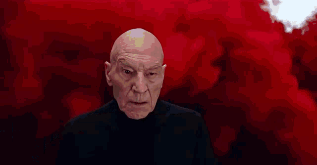 a bald man in a suit and tie is sitting in a chair making a funny face .