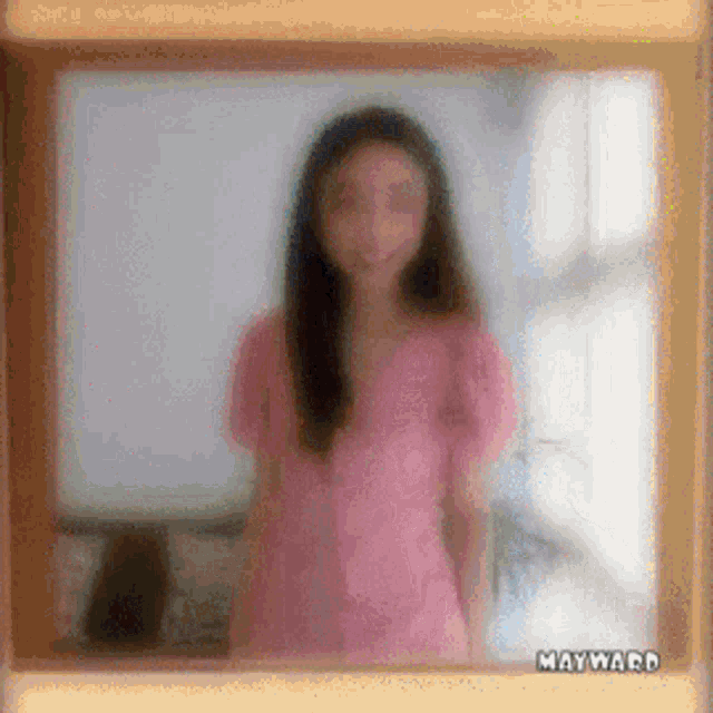 a blurry picture of a woman in a pink shirt with mayward on the bottom