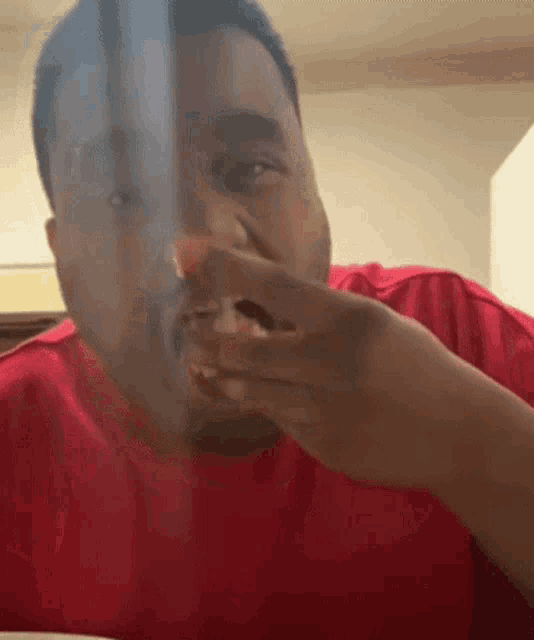 a man in a red shirt is eating a piece of food with his hand .