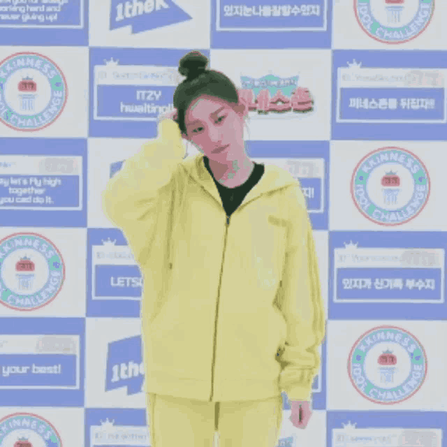 a person in a yellow jacket is standing in front of a wall that says " kindness cool challenge "