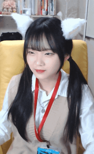 a girl with pigtails and cat ears is sitting on a yellow chair