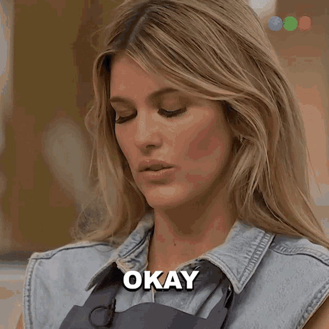 a woman in a denim shirt says okay in front of her