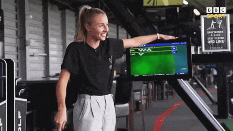 a woman stands in front of a screen that says bbc sport
