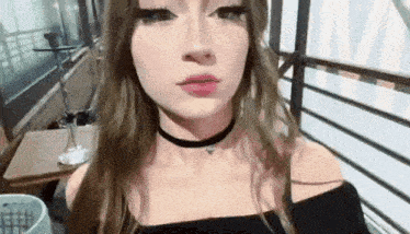 a young woman wearing a choker is making a funny face .