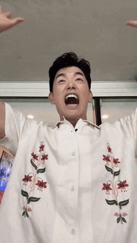 a man wearing a white shirt with red and green flowers on it