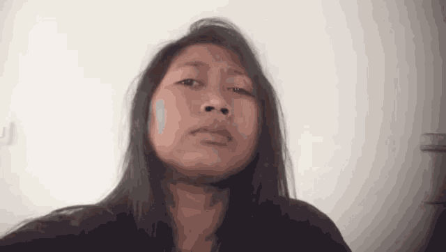 a woman with long hair is taking a selfie and making a funny face .